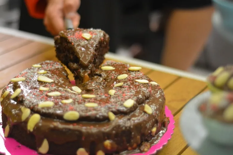 Healthy vegan chocolate cake slice topped with chocolate forsting and almonds