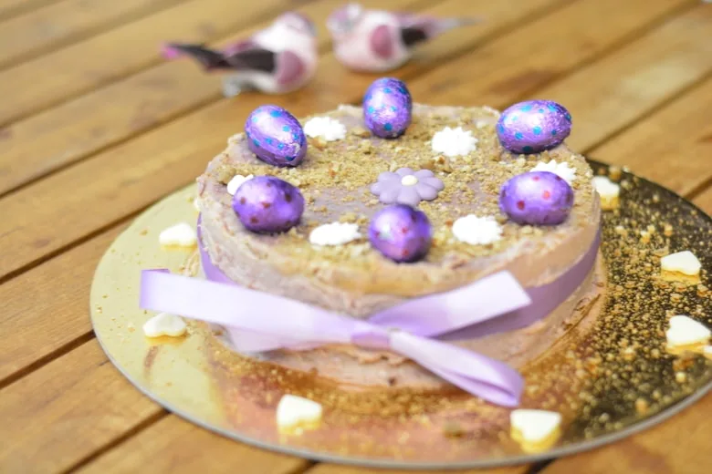 An easter carrot cake decorated with purple eggs and ribbons